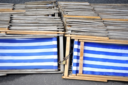 Blue and white striped deckchairs stacked and padlocked togeather on the groundの写真素材