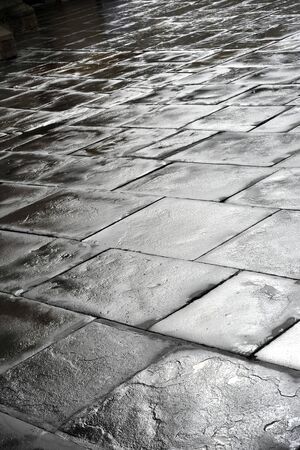 wet square flagstones photographed against the lightの写真素材