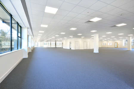 an empty office area available with grey carpet and lights onの写真素材