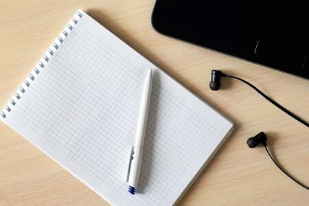 On the table are a new notebook for notes, a ballpoint pen, a laptop, and headphones. View from above. For office workの写真素材