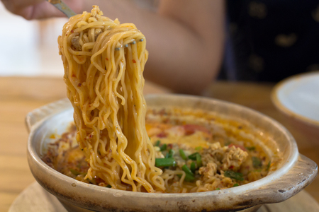 Tom Yum Kung with noodles and seafood, popular Thai food. Tom Yum Goong Spicy Sour Soup on wooden table top view, Thai local foodの写真素材