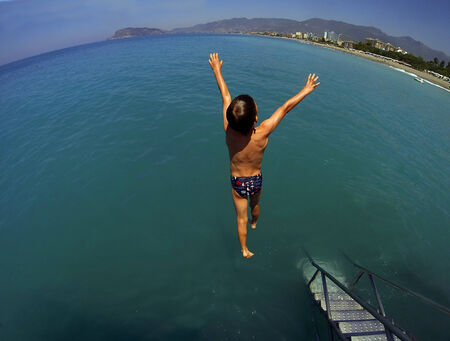 boy jumping from a height into the seaの写真素材
