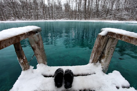 Winter swimming in blue lake. Sandals swimmer on white snowの写真素材