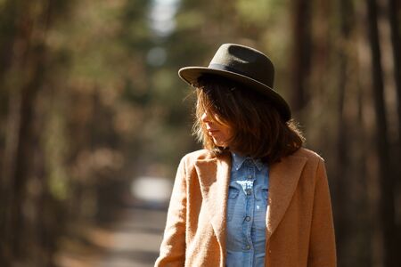 Portrait of a girl in a hat and coat in the autumn forestの写真素材