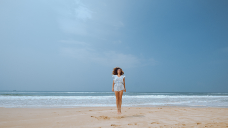 Girl jumping to the sky on the beach near the oceanの写真素材