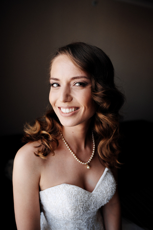 Young bride in the room with flowers. Dreamer about happy life.  White luxury dress.の写真素材