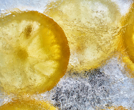 Lemon on the ice. Refreshing summer background of citrus. Yellow lemons and ice photo from above.の写真素材