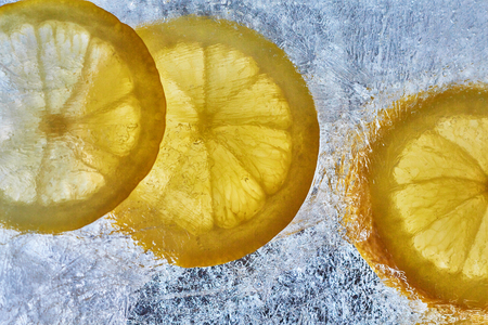 Lemon on the ice. Refreshing summer background of citrus. Yellow lemons and ice photo from above.の写真素材
