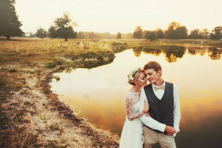 Couple in wedding attire against the backdrop of the field at sunset, the bride and groom.の写真素材