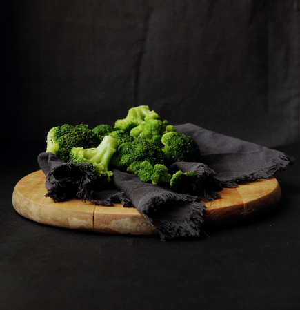 Fresh broccoli on a wooden board on a dark backgroundの写真素材