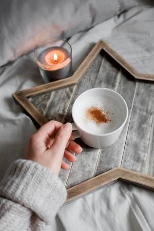 The girl is holding a cup of coffee on the background of a Scandinavian wooden trayの写真素材