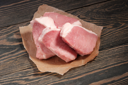 Fresh raw pork steaks on paper on a dark background.の写真素材
