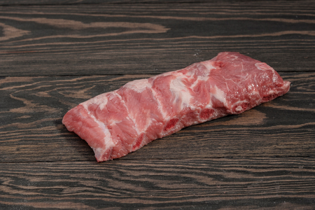 Raw whole rack of pork loin with ribs on a dark background.の写真素材
