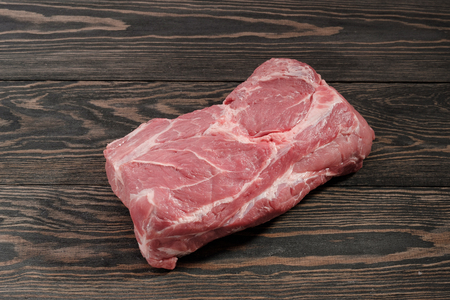 A piece of raw pork neck. Pork tenderloin on paper on a dark tableの写真素材