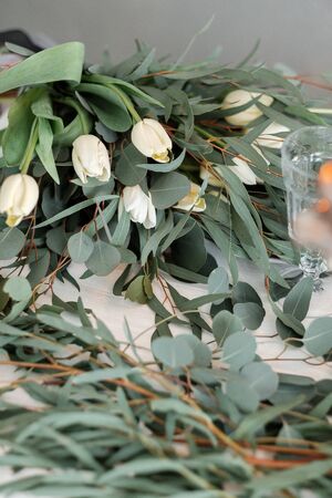 white tulips lie on a light background. Delicate spring bouquet with green leavesの写真素材