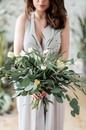 A lush bouquet of eucalyptus and tulips in the hands of a woman. Rustic Styleの写真素材