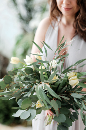 A lush bouquet of eucalyptus and tulips in the hands of a woman. Rustic Styleの写真素材