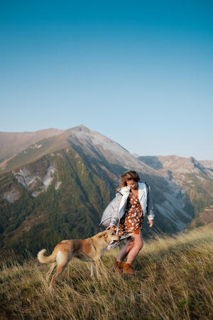A girl is walking with a dog in the mountains with a beautiful viewの写真素材