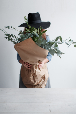 Girl in a hat with a bouquet of eucalyptus in hands. girl florist holding eucalyptusの写真素材