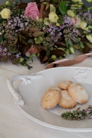 A beautiful cookie on a platter. Flowers in the background. Lilacの写真素材