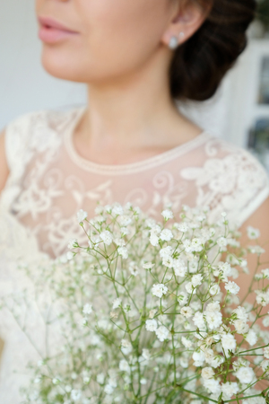 A girl in a wedding dress is holding a bouquet of gypsophilaの写真素材