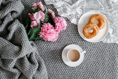 A cup of coffee and peonies on a gray background. Flat-lay of cup of coffee with  peonies