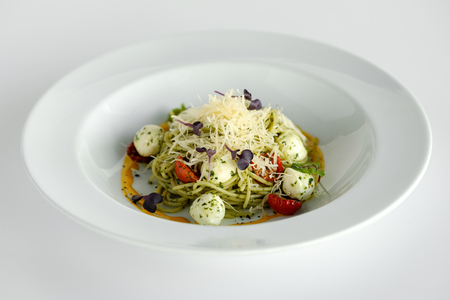 Spaghetti with basil and mozzarella cheese in a white plateの写真素材