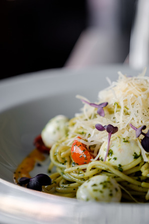 Spaghetti with basil and mozzarella cheese in a white plateの写真素材