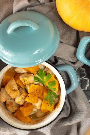 Roast pumpkin and chicken with spices in a blue pan on a wooden table, top view. On the table are pumpkins. Thanksgiving conceptの写真素材