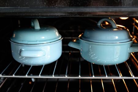 two blue pots in the oven. Cooking concept. dark backgroundの写真素材