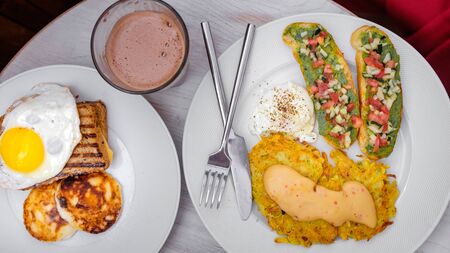 breakfast for two. fried eggs, toast, curd cheese, bruschettas with vegetables, and hash brown with sauce.White background.の写真素材