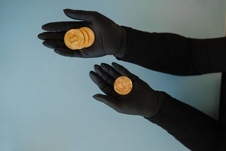 Golden Bitcoin in hand in black rubber glove.Symbol of a new virtual currency .の写真素材