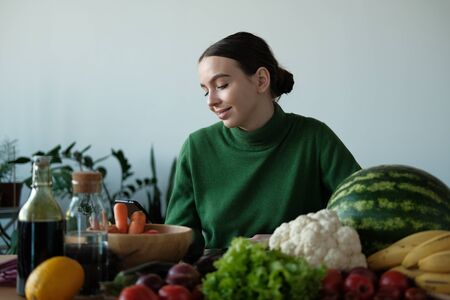 A young girl in a green sweater and Christmas hat is looking for a recipe for cooking on a...
