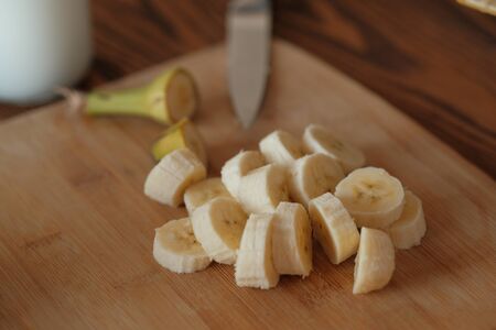 Girl cuts a banana for smoothie. Sliced banana closeup. Ingredients for smoothies. The concept of healthy eating and dieting.の写真素材