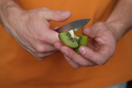 Man cuts kiwi for smoothie. Sliced kiwi close-up. The concept of healthy eating and dieting.の写真素材