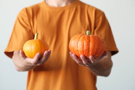 Pumpkin in male hands on orange background. The concept of autumn, halloweenの写真素材