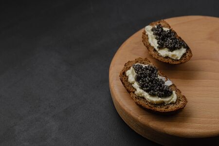 Sandwich with black sturgeon caviar on black background. Luxurious black caviar. Free space for textの写真素材