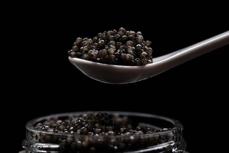 Black sturgeon caviar on a spoon. Luxurious black caviar. Sturgeon caviar in a glass jarの写真素材