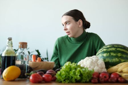 A young girl in a green sweater and Christmas hat is looking for a recipe for cooking on a...