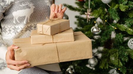 Womans hands hold christmas or new year decorated gift box. Merry Christmas and Happy Holidays!