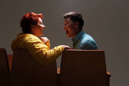 Studio portrait of cheerful couple sitting and chatting on chairs indoors
