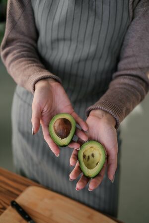 Female hands holding a fresh ripe avocado. Healthy eco food. The product of organic farming. cooking...