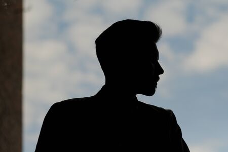 silhouette of a young man against the sky. anonymous. chief executive. businessman. black cash