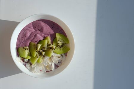 berry smoothie bowl with kiwi blueberries and coconut slices.on white background. isolatedの写真素材