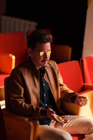 A young man holds a golden bitcoin in the eye sockets. Cryptocurrency Coins - Bitcoin. holds bitcoins in his hands.の写真素材