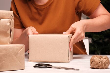 Womans hands wrapping Christmas gift, close up. Unprepared christmas presents on wooden background....