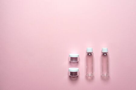 Travel set of bottles and jars on a pink background. View from above. Ecology. Plastic