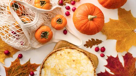 pumpkin cheesecake with persimmon, top view. Autumn composition with leaves and berries. Thanksgiving concept. Halloweenの写真素材