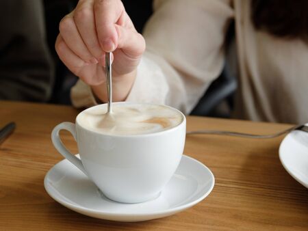 girl stirs cappuccino with a spoon. close-up. Coffee house. tasty coffee