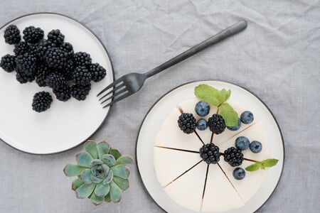 delicious classic cheesecake decorated with berries and a plate with blackberries. Top view.